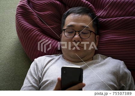 寝ながらスマホを見る男性 寝ながらスマホを見る男性 75507389