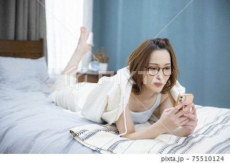 ベッドルーム　スマホを操作する女性 75510124