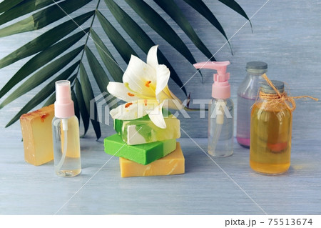 Soap, spray, lily flower, glass bottles with aromatic oil on a wooden table, spa, natural cosmetics, healthy lifestyle 75513674