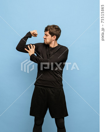 Portrait of athletic Caucasian man in black attire isolated on blue background. 75515865
