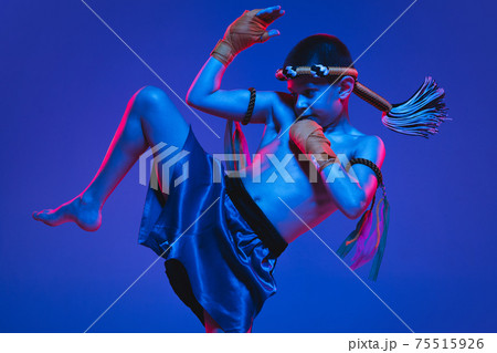 Young boy thai boxer training over blue background in neon light. Young boy thai boxer training over blue background in neon light. 75515926