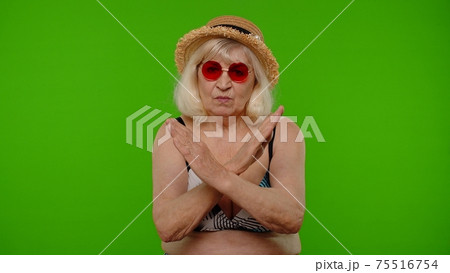 Senior woman traveler in red sunglasses showing stop sign, dislike gesture, bad idea, wrong choice Senior woman traveler in red sunglasses showing stop sign, dislike gesture, bad idea, wrong choice 75516754