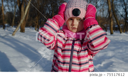 Cheerful child girl shows wow delight effect gesture, kid raising hands in surprise in winter park 75517612