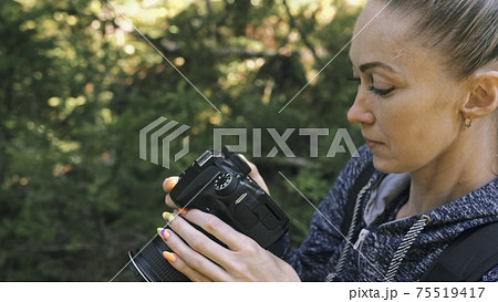 Traveler photographing scenic view in forest. One caucasian woman shooting close up look. Girl take photo video on dslr mirrorless camera. Traveler photographing scenic view in forest. One caucasian woman shooting close up look. Girl take photo video on dslr mirrorless camera. 75519417