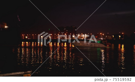 Luxurious modern private yacht and boat at the pier at night. Colorful lights of city glow shine reflected in water wave at nighttime. Luxurious modern private yacht and boat at the pier at night. Colorful lights of city glow shine reflected in water wave at nighttime. 75519592