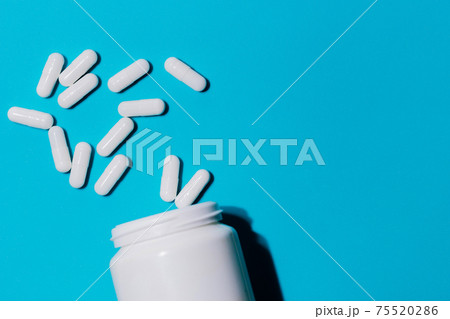 container and white pills on a blue background . 75520286