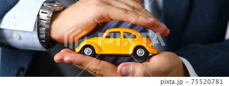 Male arm in suit and tie cover yellow toy car Male arm in suit and tie cover yellow toy car 75520781
