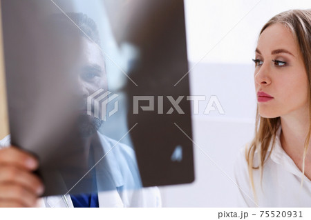 Mature male doctor hold in arm and look at xray photography Mature male doctor hold in arm and look at xray photography 75520931