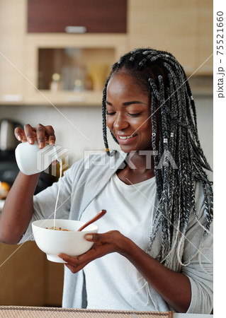 Woman adding milk to cereals 75521660