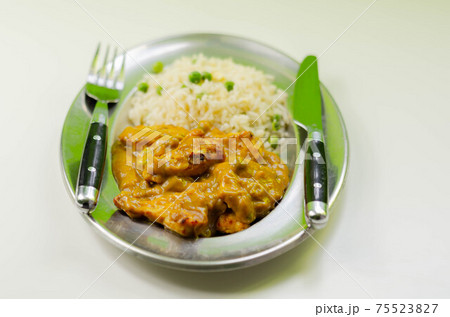 Roasted chicken breast pieces in a mildly spiced coconut curry sauce with fried rice with peas and egg 75523827