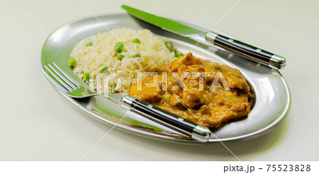 Roasted chicken breast pieces in a mildly spiced coconut curry sauce with fried rice with peas and egg 75523828