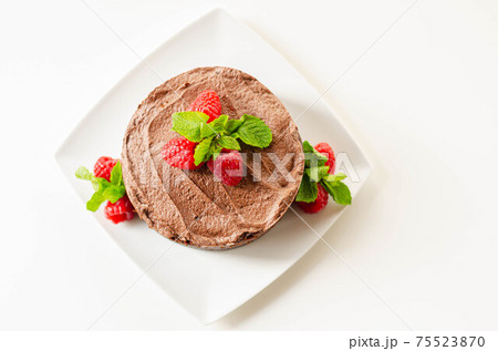 Gluten free tasty round cake based on Belgian chocolate decorated with fresh raspberries and mint 75523870