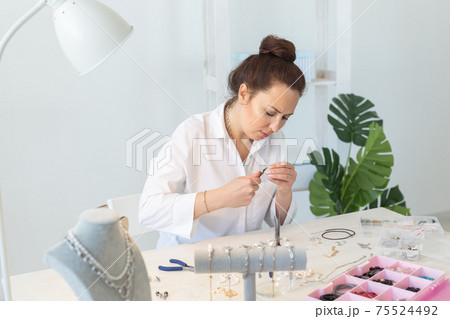 Professional jewelry designer making handmade jewelry in studio workshop. Fashion, creativity and handmade concept Professional jewelry designer making handmade jewelry in studio workshop. Fashion, creativity and handmade concept 75524492