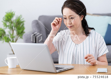 老眼 画面がよく見えずに老眼鏡をかけてパソコンを見るシニア女性 老眼 画面がよく見えずに老眼鏡をかけてパソコンを見るシニア女性 75524618