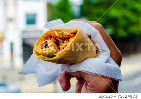 Chicken breast with piri piri sauce and lettuce in a chili tortilla wrap in the hand 75524973