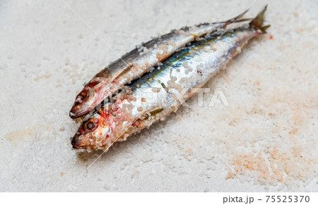 Whole raw organic mackerel fish with sea salt lying on a flat surface 75525370