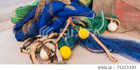 Industrial Fishing Equipment Fishnets and Fishing Lines lying on concrete in the port 75525395