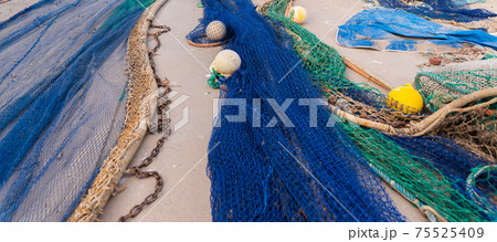 Industrial Fishing Equipment Fishnets and Fishing Lines lying on concrete in the port 75525409