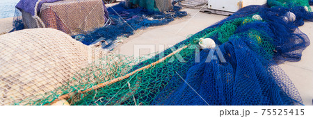 Industrial Fishing Equipment Fishnets and Fishing Lines lying on concrete in the port 75525415