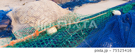 Industrial Fishing Equipment Fishnets and Fishing Lines lying on concrete in the port 75525416
