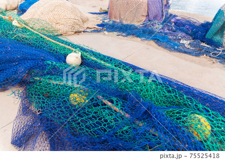 Industrial Fishing Equipment Fishnets and Fishing Lines lying on concrete in the port 75525418