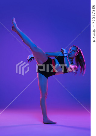 Young female MMA fighter posing isolated over blue-pink background in neon light 75527886
