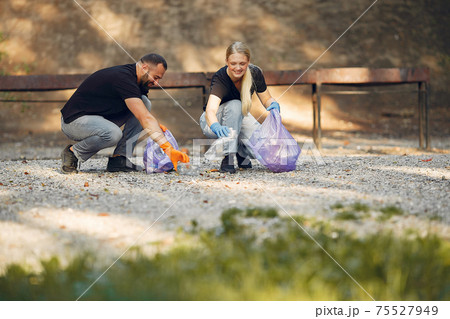 Couple collects garbage in garbage bags in park 75527949