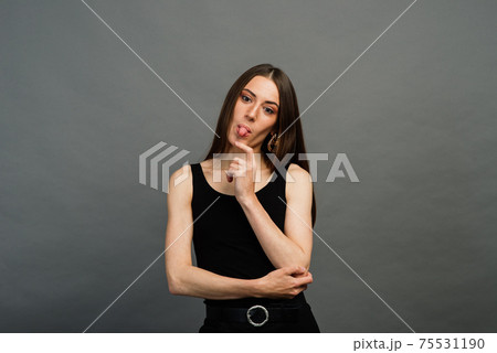 Cheerful young beautiful girl smiling winking showing tongue looking at camera over grey background. Emotional. Cheerful young beautiful girl smiling winking showing tongue looking at camera over grey background. Emotional. 75531190