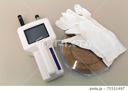 Silicon Wafer in plastic holder box on a table with particle counter near. 75531497