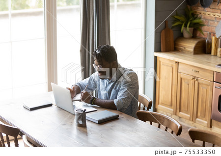 Confident black guy hold virtual business meeting online using laptop Confident black guy hold virtual business meeting online using laptop 75533350