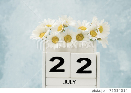 White cube calendar for july decorated with daisy flowers on blue 75534014