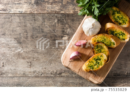 Garlic bread slice on wooden table.  75535029