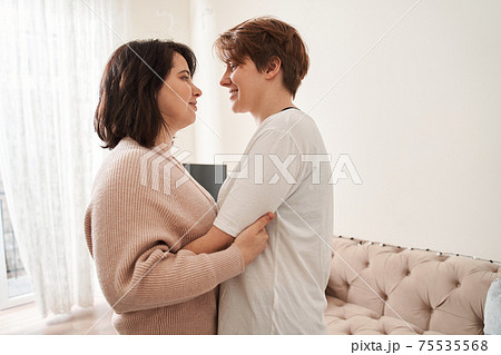 Girl keeping smile on her face while standing close to her female partner Girl keeping smile on her face while standing close to her female partner 75535568