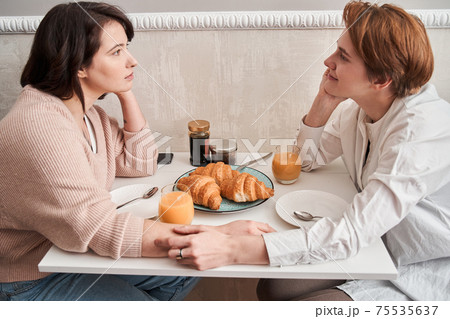Lesbian couple talking during breakfast while sitting at the kitchen 75535637