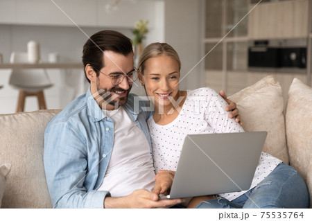 Smiling young couple relax together using laptop Smiling young couple relax together using laptop 75535764