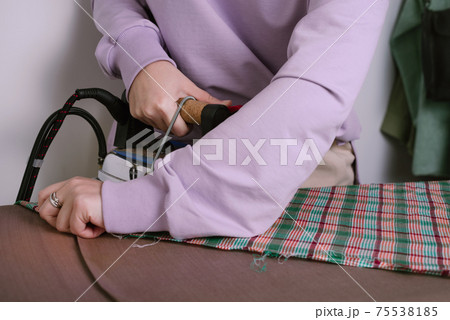 Closeup of female ironing plaid fabric in sewing workshop Closeup of female ironing plaid fabric in sewing workshop 75538185