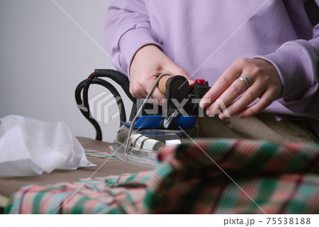Closeup of female ironing plaid fabric in sewing workshop 75538188
