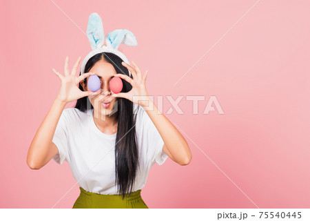 woman smiling wearing rabbit ears holding colorful Easter eggs front eyes woman smiling wearing rabbit ears holding colorful Easter eggs front eyes 75540445