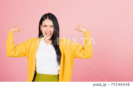 woman raises arms biceps confident showing power 75540448