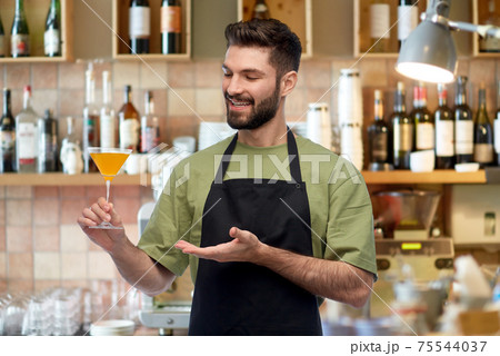 happy barman in apron with glass of cocktail happy barman in apron with glass of cocktail 75544037