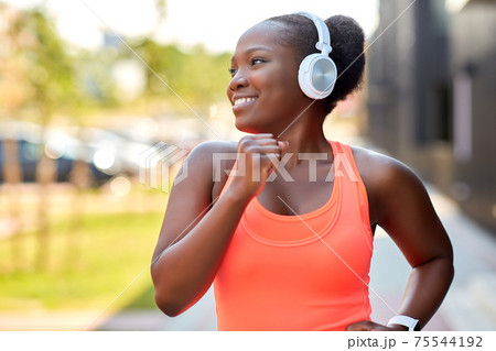 happy african woman in headphones running outdoors happy african woman in headphones running outdoors 75544192