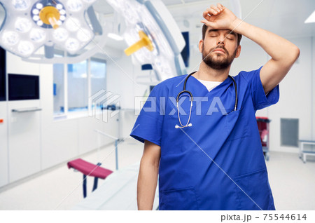 tired doctor or male nurse at surgery in hospital tired doctor or male nurse at surgery in hospital 75544614