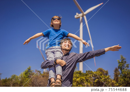 Alternative energy, wind farm and happy time with your family. Happy father carrying his son on shoulders is on vacation and escape to nature. Father carrying son on shoulders and waving their arms 75544688