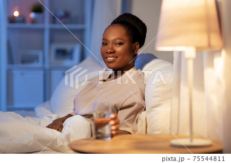 african american woman drinking water at night 75544811