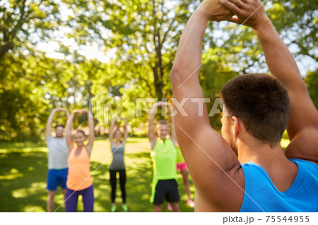happy people exercising with trainer at park 75544955
