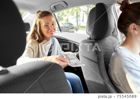 female passenger passing money to car driver female passenger passing money to car driver 75545089