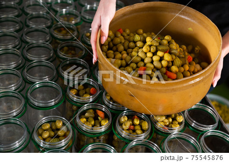 Female hands filling glass jars with pickled olives Female hands filling glass jars with pickled olives 75545876