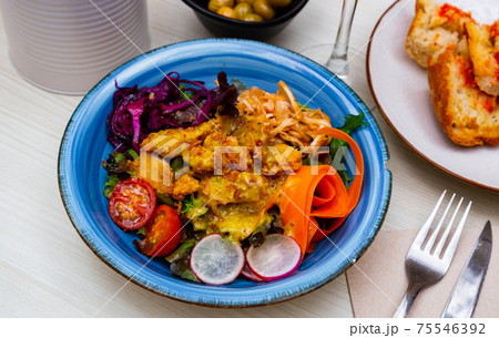 Greek salad with vinaigrette dressing topped with grilled chicken 75546392