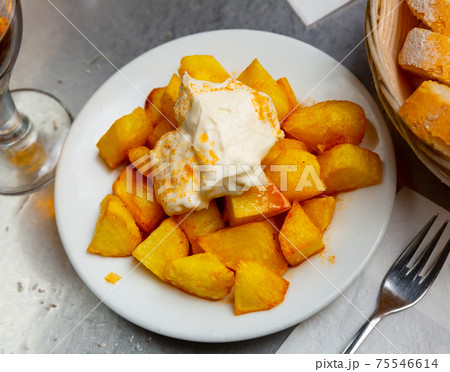 Top view of Patatas bravas, Spanish dish of fried potatoes served with cheese sauce and spicy sauce with paprika Top view of Patatas bravas, Spanish dish of fried potatoes served with cheese sauce and spicy sauce with paprika 75546614