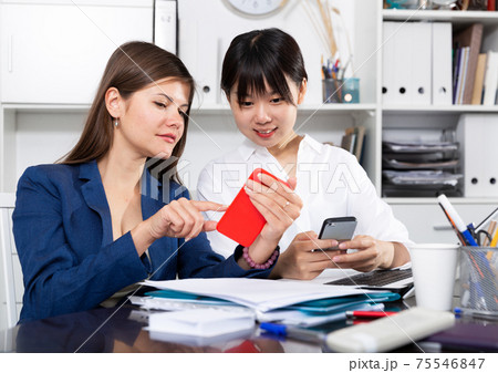 Two businesswomen working with smartphone in the office Two businesswomen working with smartphone in the office 75546847